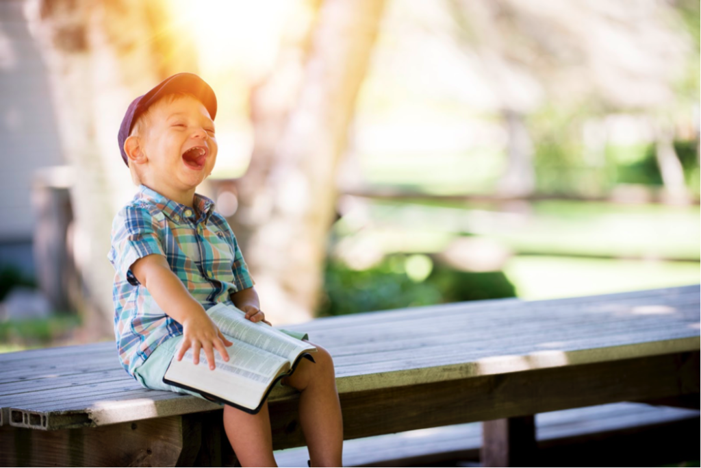 little boy laughing on bench